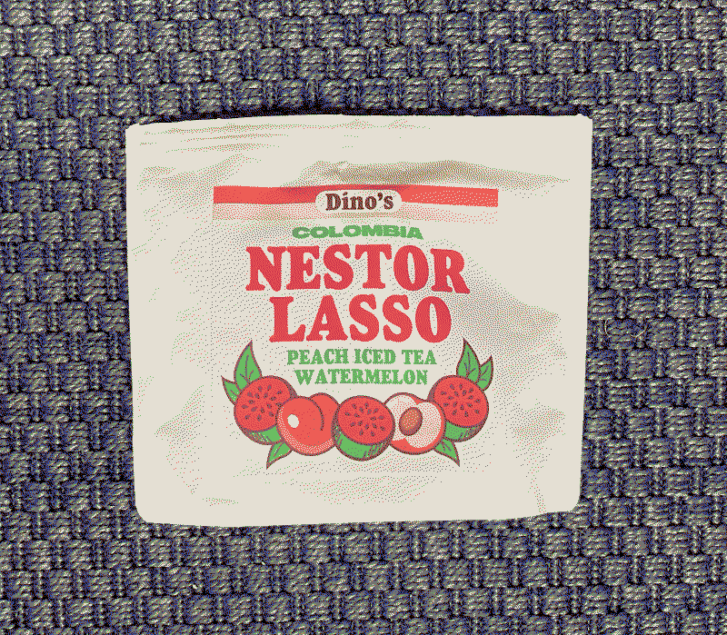 Rectangular white coffee packaging on a blue carpeted background that says 'Dino's Colombia Nestor Lasso Peach Iced Tea Watermelon', there are illustrations of peaches and watermelons on the packaging.