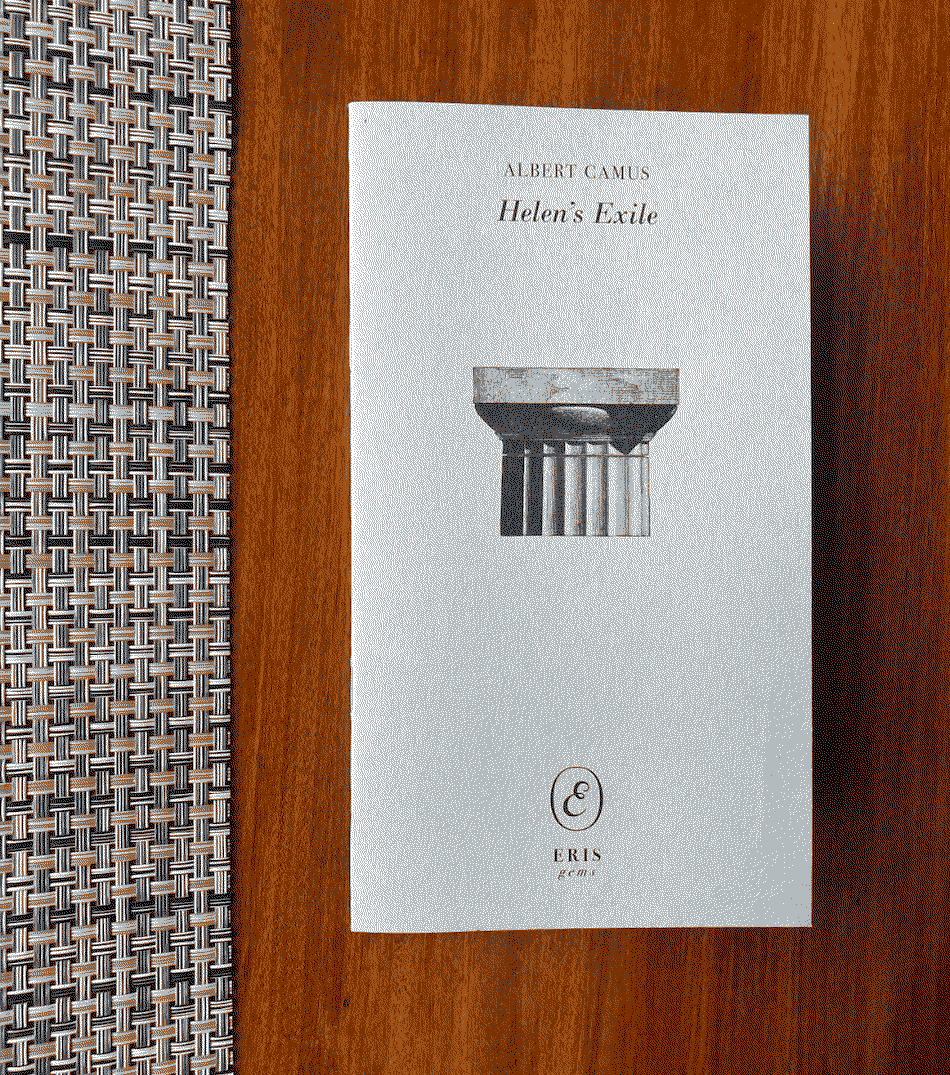 Long grey book with a doric capital on the cover against a dark wood background.