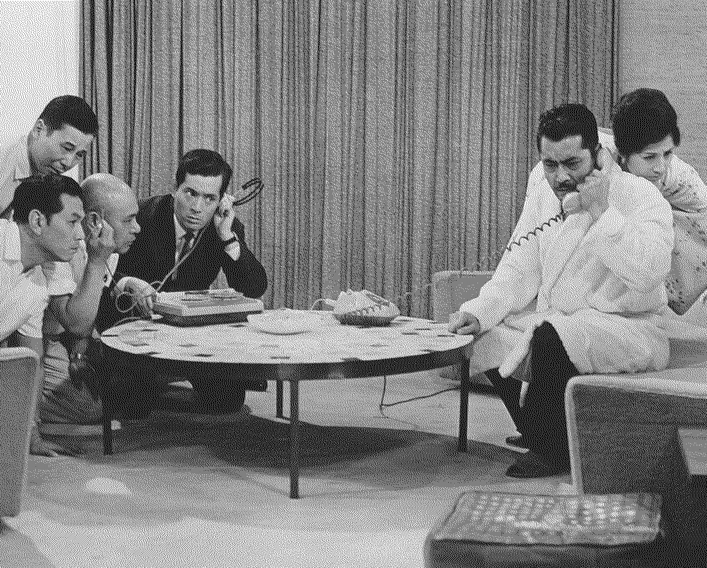 Six men and a woman listening intensively to a phone call.