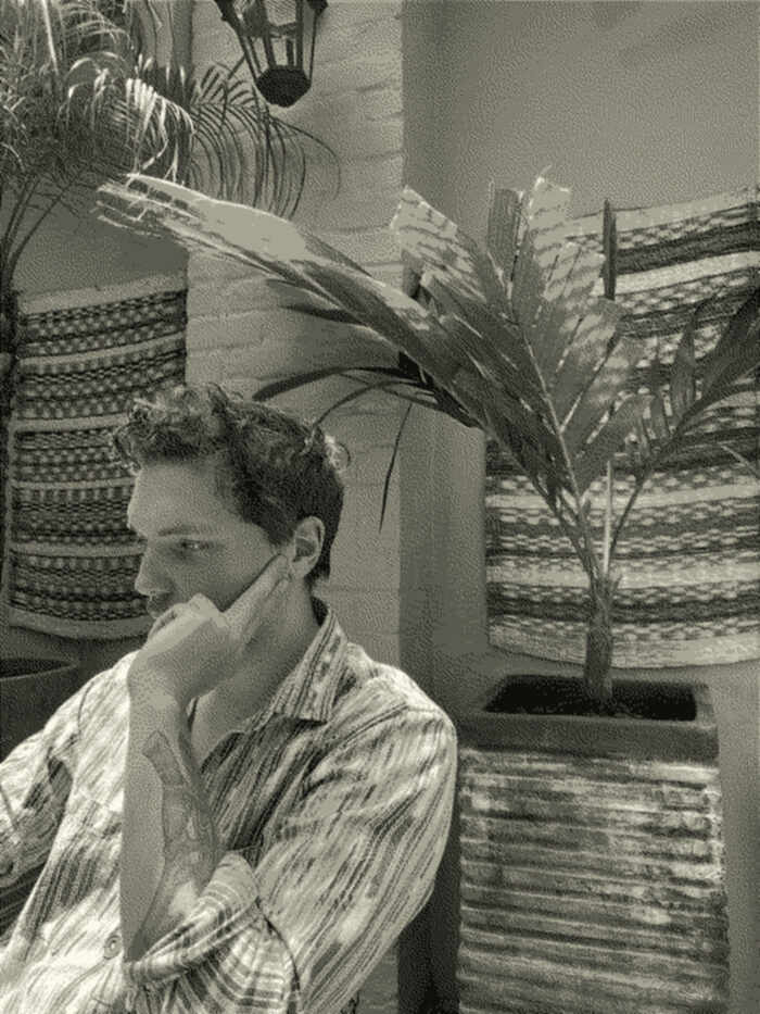 Marc sitting down by a small palm tree, looking pensive