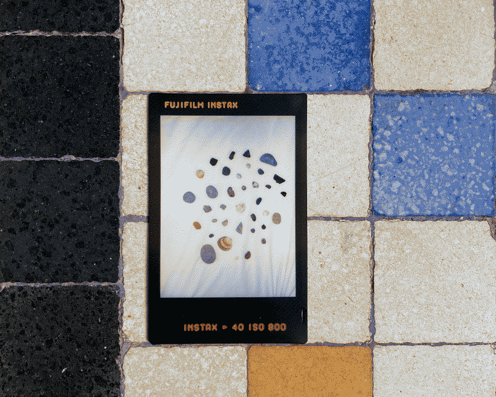 A polaroid picture of rocks and shells on a tile floor
